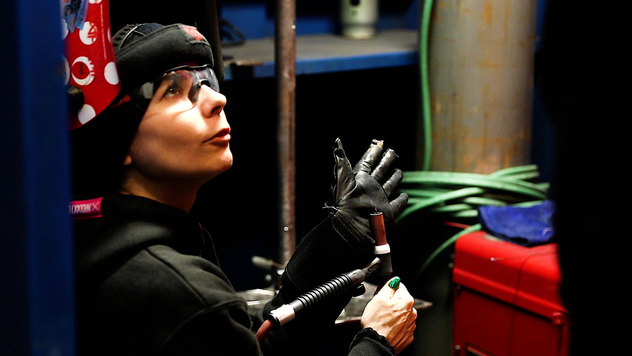 Worker preparing welding torch in industrial workshop